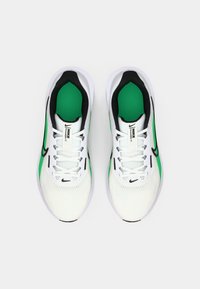 White athletic shoes with green accents and black details. Mesh upper, flat laces, and prominent Nike branding on the tongue and sides.
