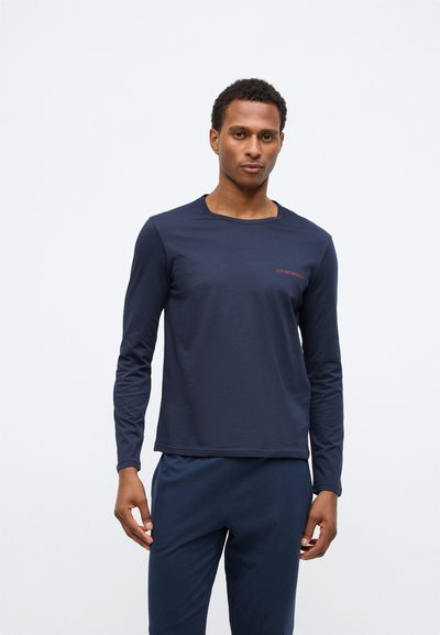 Marineblauwe langemmouw t-shirt van zachte stof, met een ronde hals en een klein rood logo op de borst, gecombineerd met bijpassende broeken.