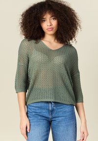 Olivgrüner Strickpullover mit einem lockeren, luftigen Design, V-Ausschnitt und 3/4-Ärmeln. Besitzt eine offene Webstruktur und einen gerippten Saum.