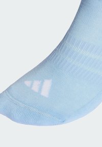 Světle modrá kotníková ponožka z měkkého textilu, s hladkou texturou a bílým logem značky u špičky, s jemným proužkovaným vzorem.