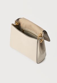 Bež usnjena torbica z odprtim poklopcem, zlatimi jermeni iz verige in vidnim notranjim žepom z zadrgo na belem ozadju.