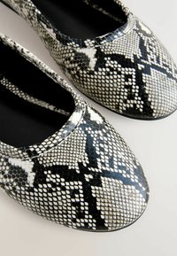 Čierne a biele balerínky s hadím vzorom, hladkým povrchom, zaoblenou špičkou a elastickým otvorom pre jednoduché obúvanie. Mäkká vnútorná podšívka.