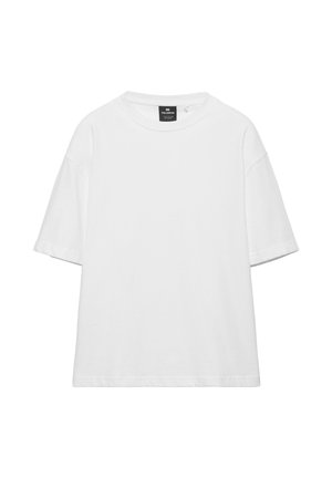 Yksinkertainen valkoinen ylisuurikokoinen lyhythihainen T-paita pyöreällä pääntiellä ja mustalla merkkilapulla kauluksen sisäpuolella.