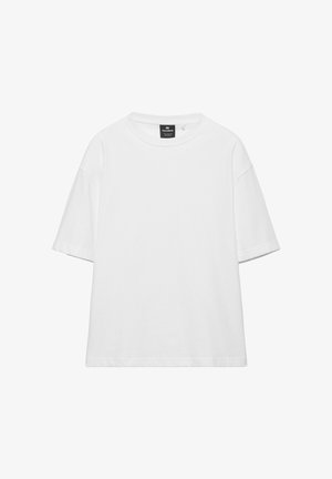 T-shirt ample blanc uni à manches courtes avec col rond et étiquette de marque noire à l'intérieur du col.