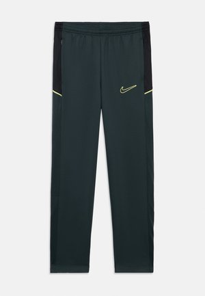 Nike sportieve broek in donker groen, met een zwart zijpaneel, gele accenten, een elastische tailleband en een logo op de linker dij. Glad materiaal.