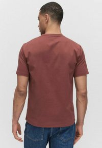 Kortærmet, rustfarvet t-shirt i blødt bomuld med klassisk rund halsudskæring. Bagsiden har et minimalistisk design uden synlige logoer.