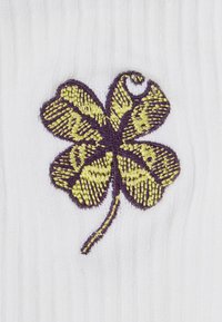 Wyhaftowany czterolistny koniczyna z żółtym i fioletowym haftem na białym, prążkowanym tle.