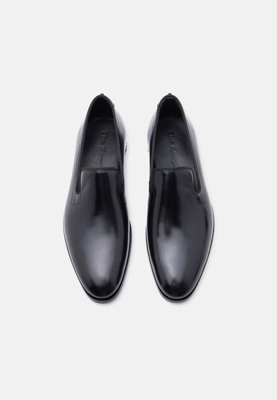 Ζευγάρι λαμπερών μαύρων δερμάτινων επίσημων παπουτσιών χωρίς κορδόνια με στρογγυλεμένες μύτες, από πάνω, σε λευκό φόντο.