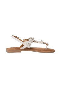 Sandali bianchi con decorazioni floreali e perle finte su una soletta morbida marrone. Presentano un tacco piatto e una cinghia alla caviglia per supporto.
