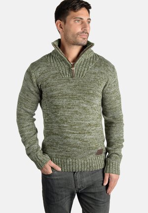 Jersey verde de punto con un cuello alto, que cuenta con un cierre de media cremallera y puños acanalados. Tejido texturizado con un patrón moteado.