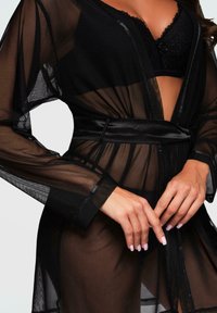 Robe in rete nera con una texture morbida, maniche lunghe, una cintura in satin e un design aperto, che mostra un delicato reggiseno in pizzo sottostante.