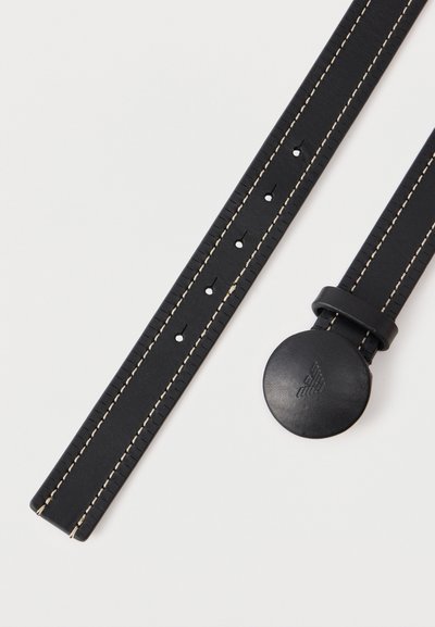 Μαύρη δερμάτινη ζώνη με κρεμ ραφές, πολλαπλές τρύπες για ρύθμιση και στρογγυλή μαύρη αγκράφα με ανάγλυφο λογότυπο με φτερά.