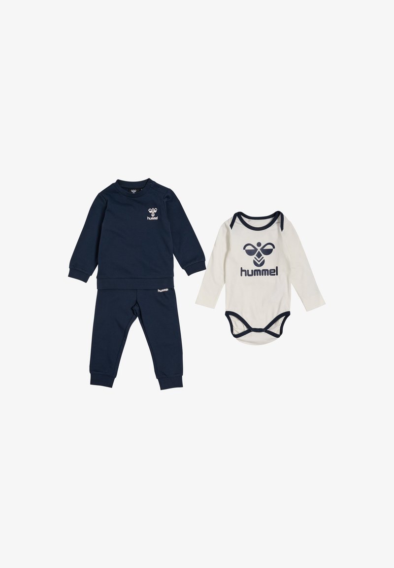 Marinblå tröja och byxor för småbarn, med en logotyp, i kombination med en krämfärgad långärmad body med marinblå detaljer och matchande logotyp.