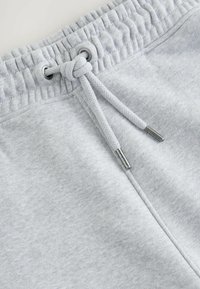 Lichtgrijze sweatpants met een elastische tailleband, verstelbare koordsluiting en metalen aglets. Zachte textuur met een gladde afwerking.