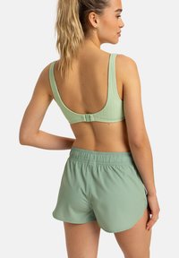 Soutien-gorge de sport en vert menthe côtelé avec des larges bretelles et un fermoir au dos, associé à un short avec taille élastique assorti, présentant une texture lisse.