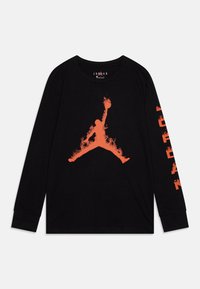 Camisa negra de manga larga hecha de algodón, con un gráfico de llamas naranjas en el centro y texto vertical en naranja en la manga izquierda.