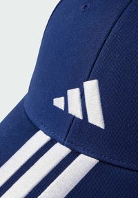 Navy blue baseball cap featuring white embroidered three-stripe logo and accents, made of textured fabric with a curved brim.