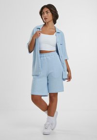 Light blue knit short set featuring a button-up shirt and elastic waistband shorts. Lightweight fabric with ribbed texture and cuffed hems.