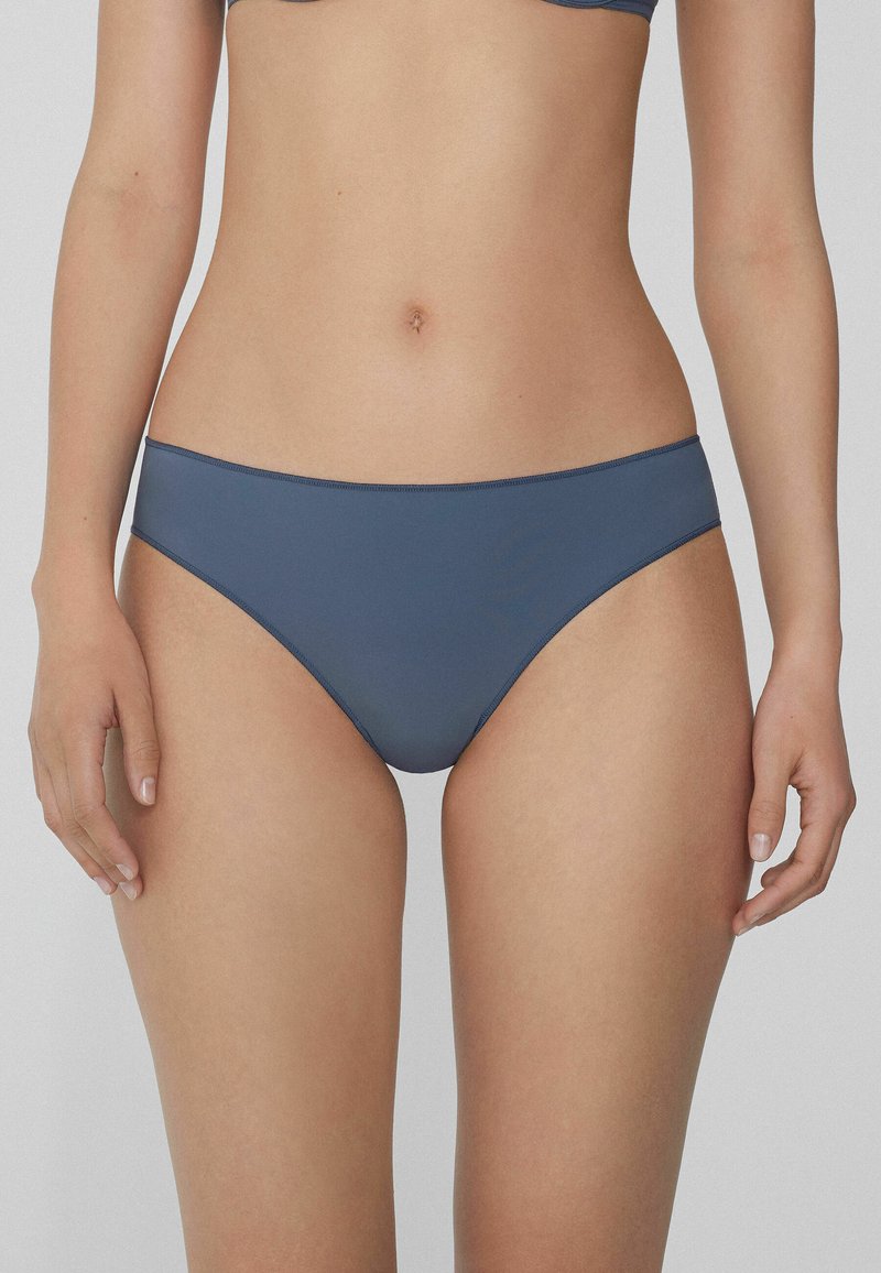 Niebieskie bikini o górze, wykonane z gładkiego materiału, z średnim stanem, minimalistycznym przeszyciem oraz jednolitym kolorem bez wzorów czy zdobień.