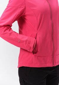 Pink softshell jacket with a zip front, side pockets, and contrasting black trim. Made from lightweight, textured fabric with a fitted design.
