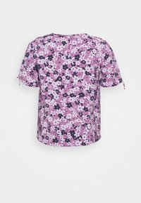 Blusa de manga corta con un patrón floral en púrpura, rosa y blanco, cierre de botón en la parte posterior y pequeñas lazadas en las mangas sobre un fondo liso.