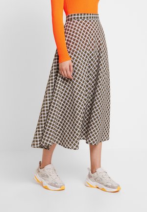 Brauner und weißer karierten Midi-Rock mit ausgestelltem Design und tailliertem Bund, kombiniert mit hellen Sneakern mit orangefarbenen Akzenten.