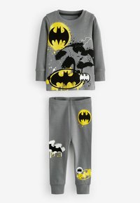 Grå bomullspyjamas i set med långa ärmar och byxor. Designen inkluderar svarta och gula Batman-logotyper med splatter-accenter.