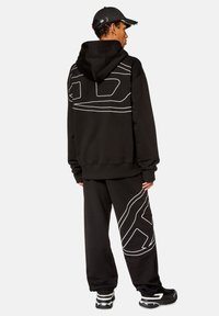 Conjunto de sudadera con capucha y pantalones de chándal de tela suave. Presenta un diseño de contorno blanco en la parte posterior de la sudadera y a lo largo de la pierna izquierda de los pantalones.