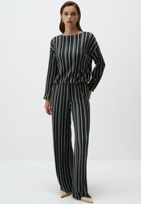 Completo a due pezzi a righe di colore verde scuro, con maniche lunghe, top a vestibilità ampia e pantaloni a gamba larga. Righe di colori rosa e crema.