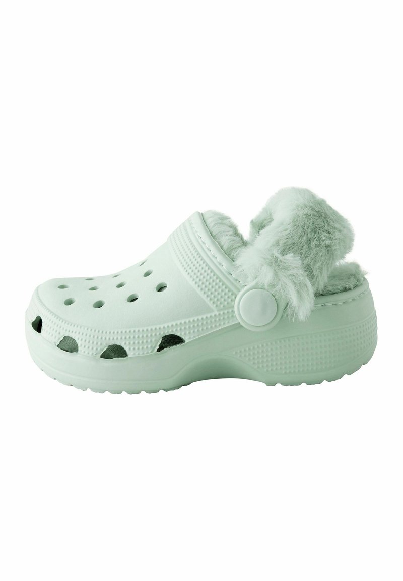 Sabot vert clair avec une doublure en fourrure douce et duveteuse. Fabriqué en matériau léger avec des trous de ventilation et une semelle texturée pour une meilleure adhérence.