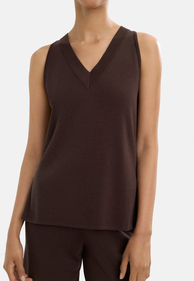 Brązowa bezrękawnik z dekoltem w serek, wykonana z miękkiego materiału dzianinowego. Projekt cechuje luźny krój oraz boczne szwy dla uzyskania gładkiego wykończenia.