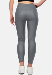 Leggings grigi realizzati in un materiale elasticizzato e morbido, con vita alta, caratterizzati da cuciture minime e un design aderente. Abbinati a scarpe bianche.