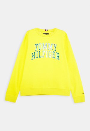 Gelbes Sweatshirt mit langen Ärmeln und dem Schriftzug „Tommy Hilfiger“ in Blau und Weiß auf der Vorderseite, gerippte Bündchen und Saum, kleines Flaggen-Logo am linken Ärmel.
