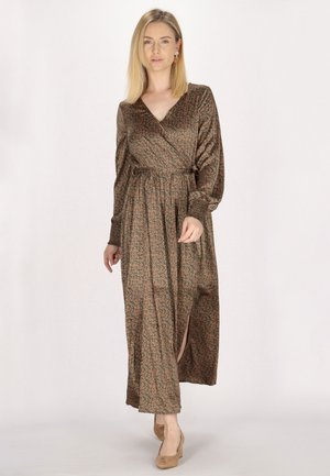 Langes, braunes Kleid mit floralem Muster, langärmlig, mit Wickelausschnitt, tailliert und mit einem oberschenkellangen Schlitz. Getragen mit beigen High Heels.