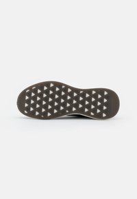 Suola di scarpa in gomma marrone con un motivo a intaglio triangolare e accenti bianchi; superficie liscia e bordi arrotondati per una migliore aderenza.