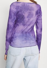 Dlouhý rukáv top v fialovém tie-dye vzoru, s kulatým výstřihem a mírně volným střihem, vyrobený z měkké, lehké tkaniny.