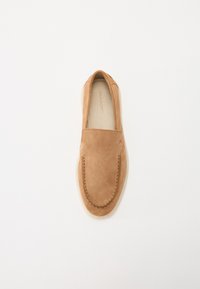 Tan semsket slip-on sko med rund tå, med stiklsete detaljer og en glatt, lys farget såle. Minimalistisk design uten synlige detaljer.