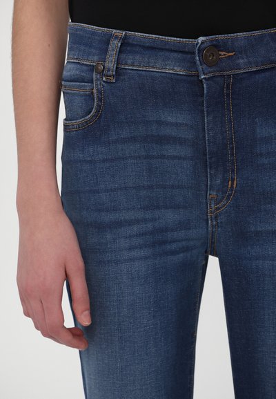 Jeans din denim albastru închis cu un design ajustat, având cusături portocalii, o buzunar frontal și o închidere cu nasture la talie.