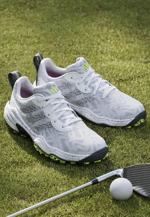 White athletic shoes with green accents and textured mesh upper, featuring lace-up design, molded heel, and rubber spikeless outsole.