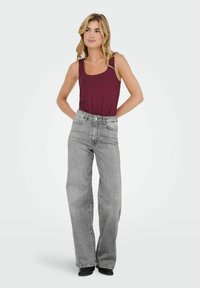 Grå bredbenede jeans og en burgunder tanktop. Jeansene har høj talje, lommer og en klassisk denim tekstur.