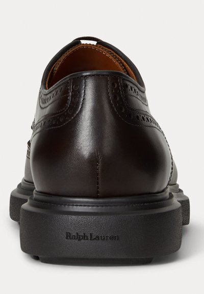 Brown leather dress shoes with an embossed pattern, rounded toe, and a sturdy black rubber sole. Features a logo on the heel.