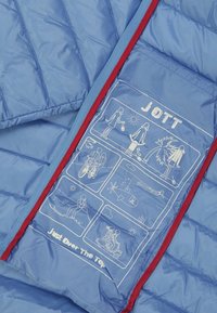 Ljustblå puffjackas insida med röd kant har vita illustrerade grafiker och text som inkluderar "JOTT" och "Just Over The Top."