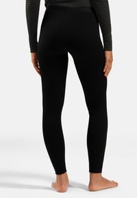 Black fitted leggings made from stretchy fabric, featuring a high waistband and tapered ankle cuffs; smooth texture with no visible seams.