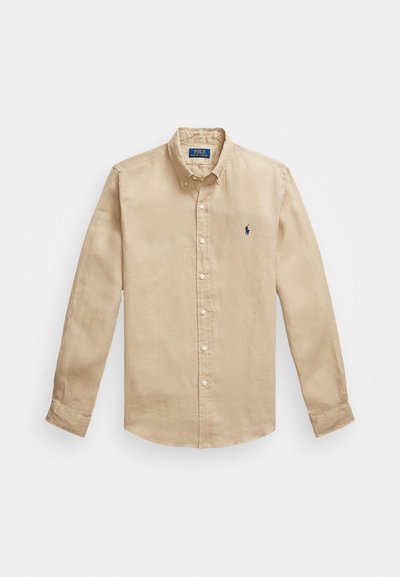 Camisa de botão de mangas longas bege, feita de algodão. Apresenta um colarinho pontudo, pequeno logótipo bordado no peito e placket de botões padrão.