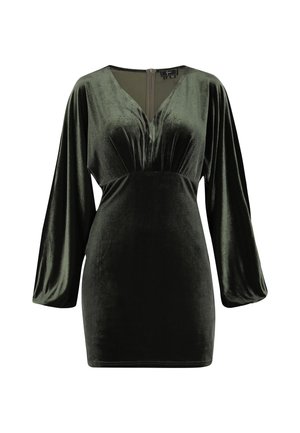 Vestido de terciopelo verde con mangas largas y anchas, escote en V profundo y detalle de costura central. Textura suave y silueta ajustada. Cierre de cremallera en la parte posterior.