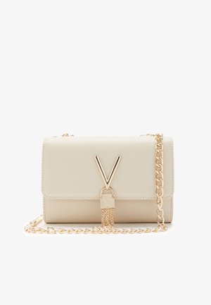 Krémová kabelka z prošívané kůže s zlatým řetízkovým popruhem, která má výrazný zlatý V-tvarovaný kovový prvek a bezpečné uzamykání.
