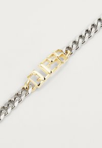 Pulsera de cadena de plata y oro que presenta eslabones entrelazados y un prominente cierre de oro con un diseño geométrico.