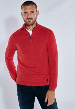 Red pullover sweater with a high collar and quarter zip. Features ribbed cuffs and hem, smooth texture, and black accent at the bottom.