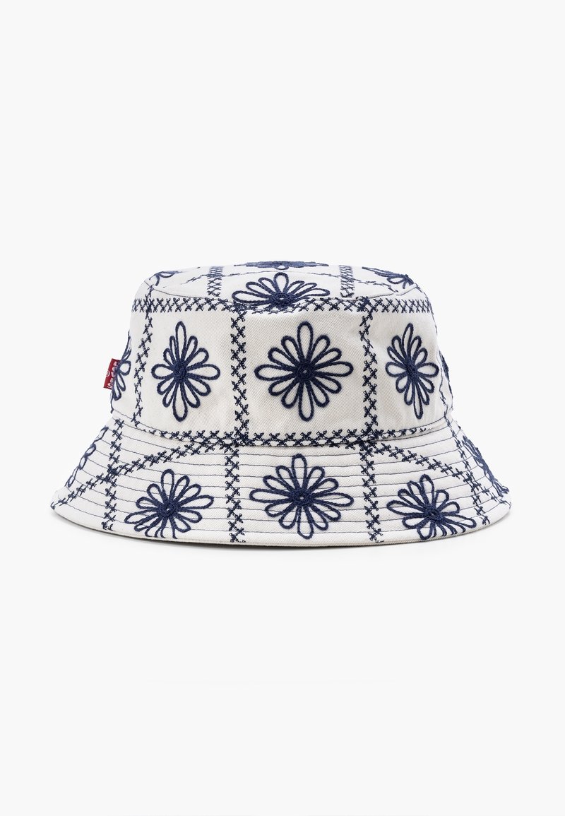 Chapeau bob blanc avec des motifs floraux brodés bleu marine disposés en grilles carrées.