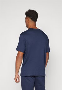 Navy blue short-sleeve t-shirt made of soft fabric, featuring a round neckline and relaxed fit, seen from the back. Simple design without patterns.